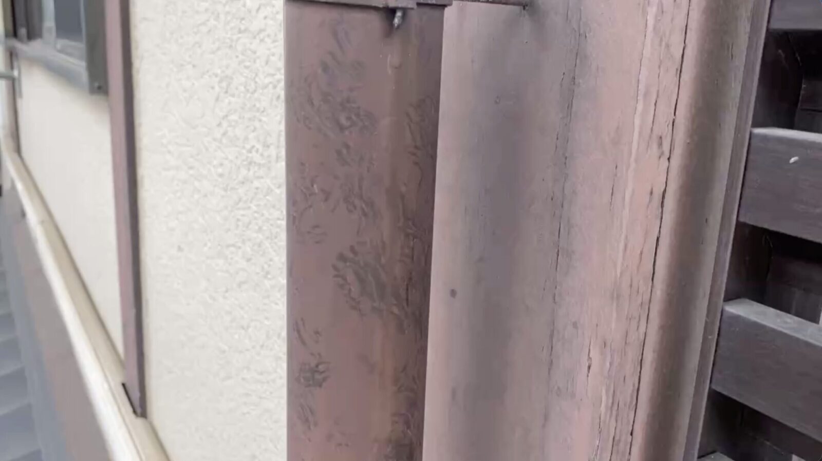 茶色の縦樋の表面に付いた、小さな足跡の列
