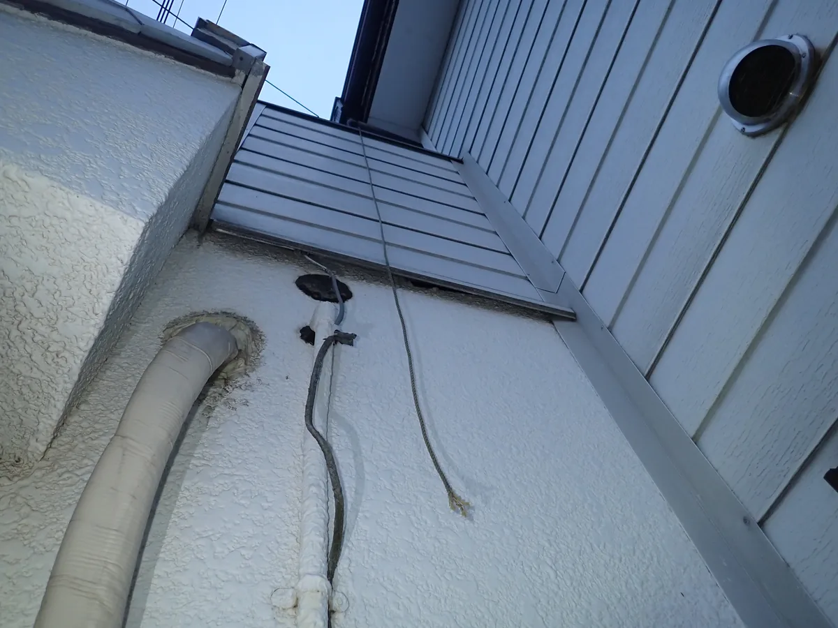 外壁を下から見上げたところ。白い配管と電線が壁の中へ入っている部分