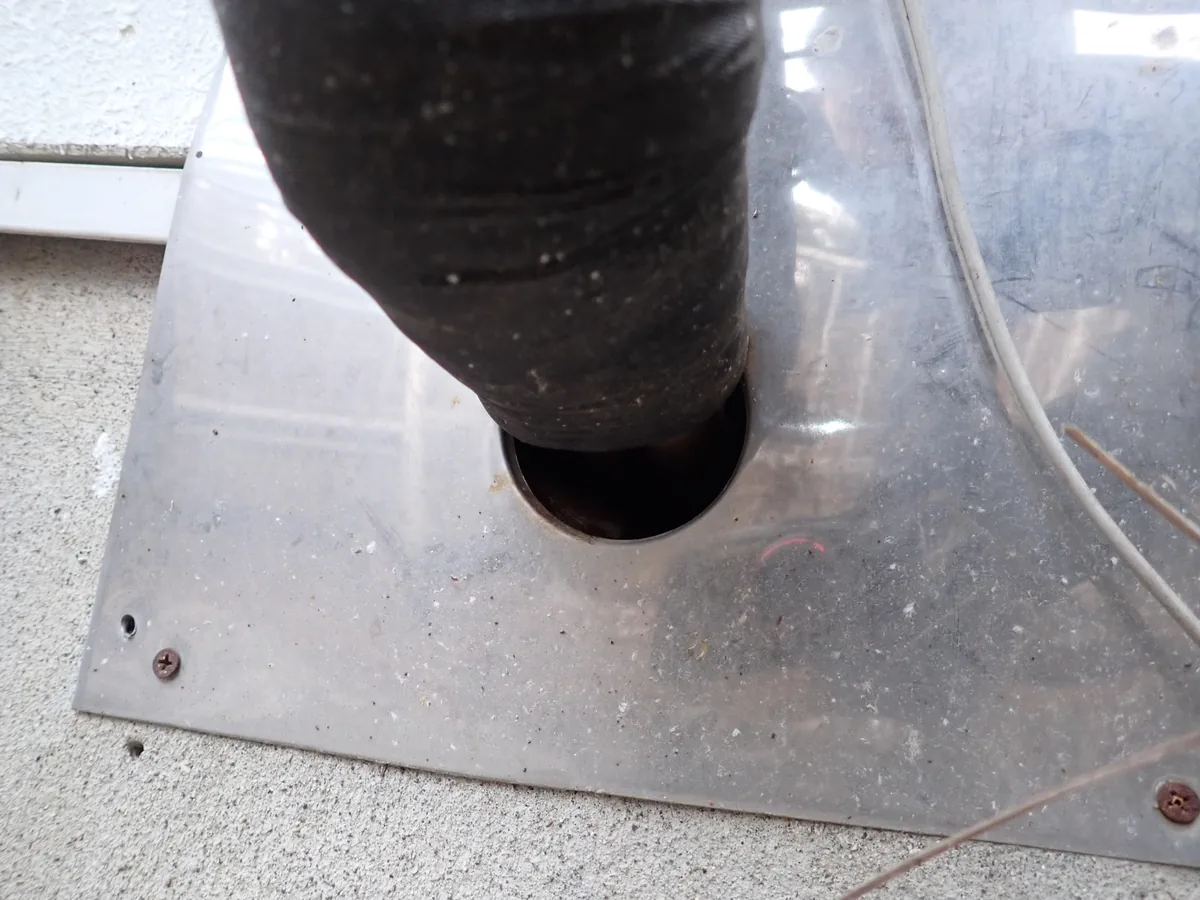 板に開けた丸い穴を黒い管が通り、穴の縁と管の間が暗く空いたところ