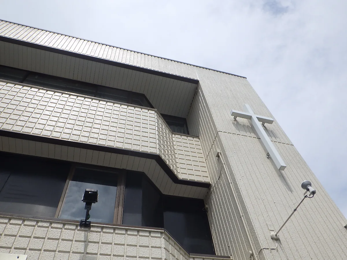 上の階ごとに軒天が張り出した、白いタイル外壁の建物を見上げた様子