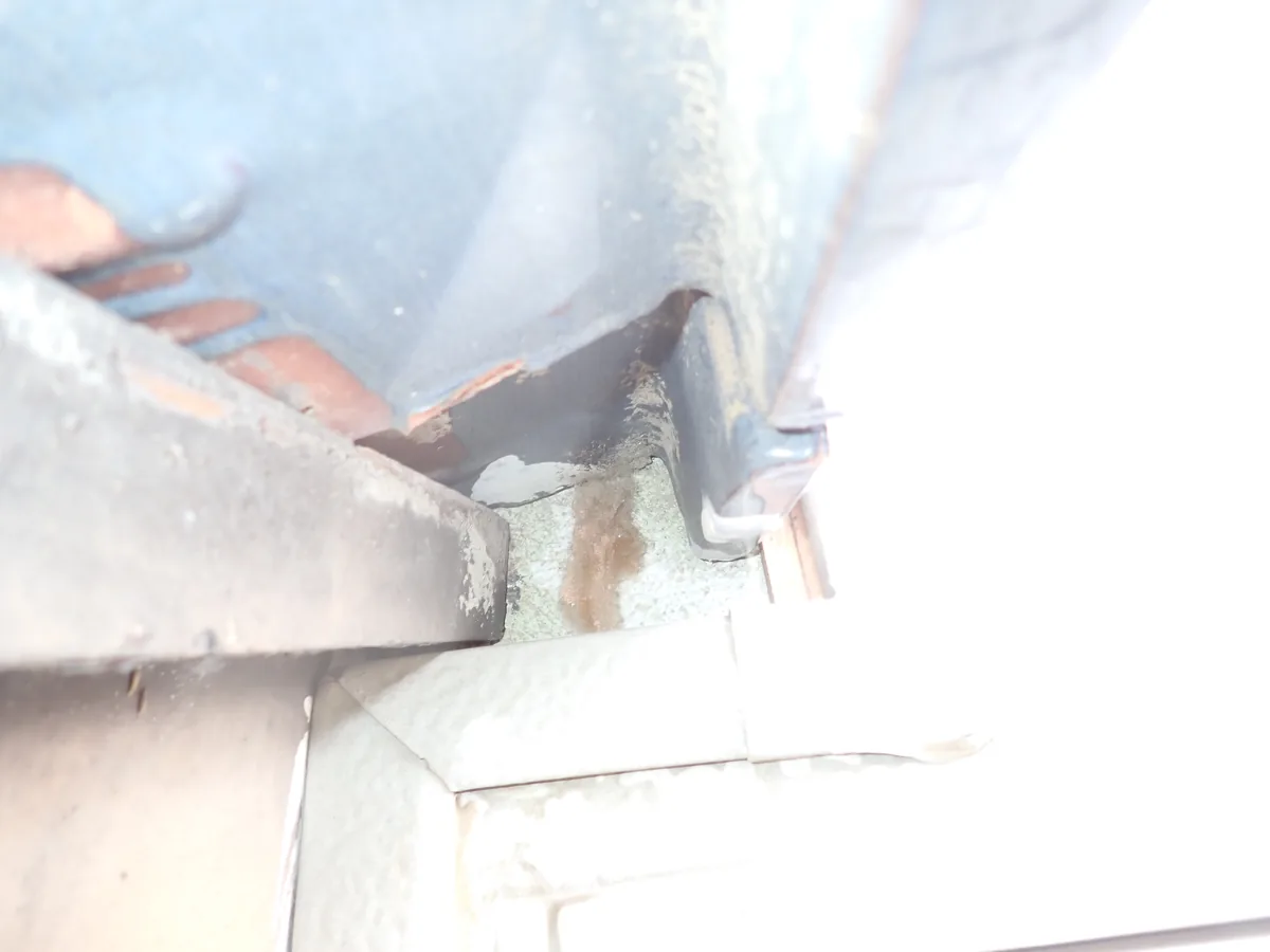 軒の角を下から見上げると、屋根の端の板と瓦の間にすき間があき、茶色いしみが筋になって付いている
