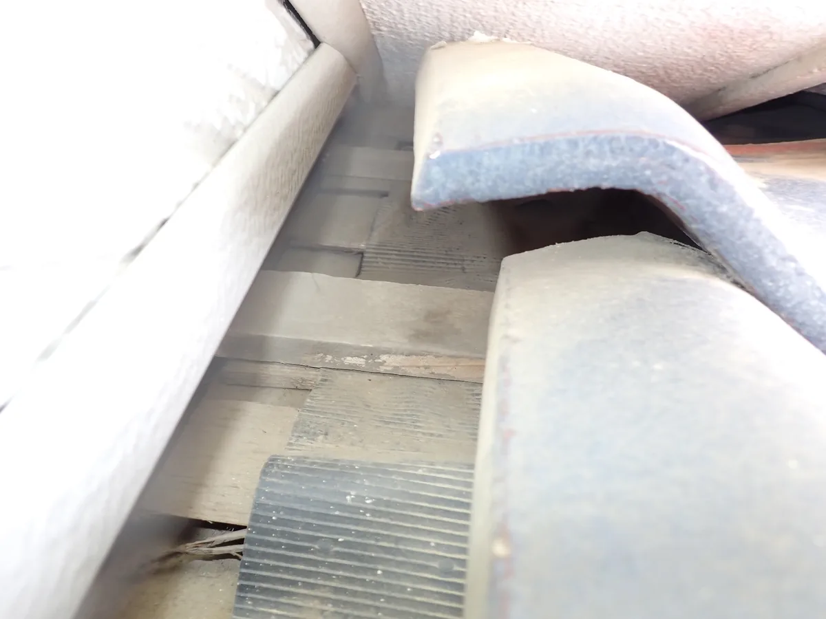 瓦の下に木の下地と奥の空間がのぞく、瓦と壁際の板金の重なり