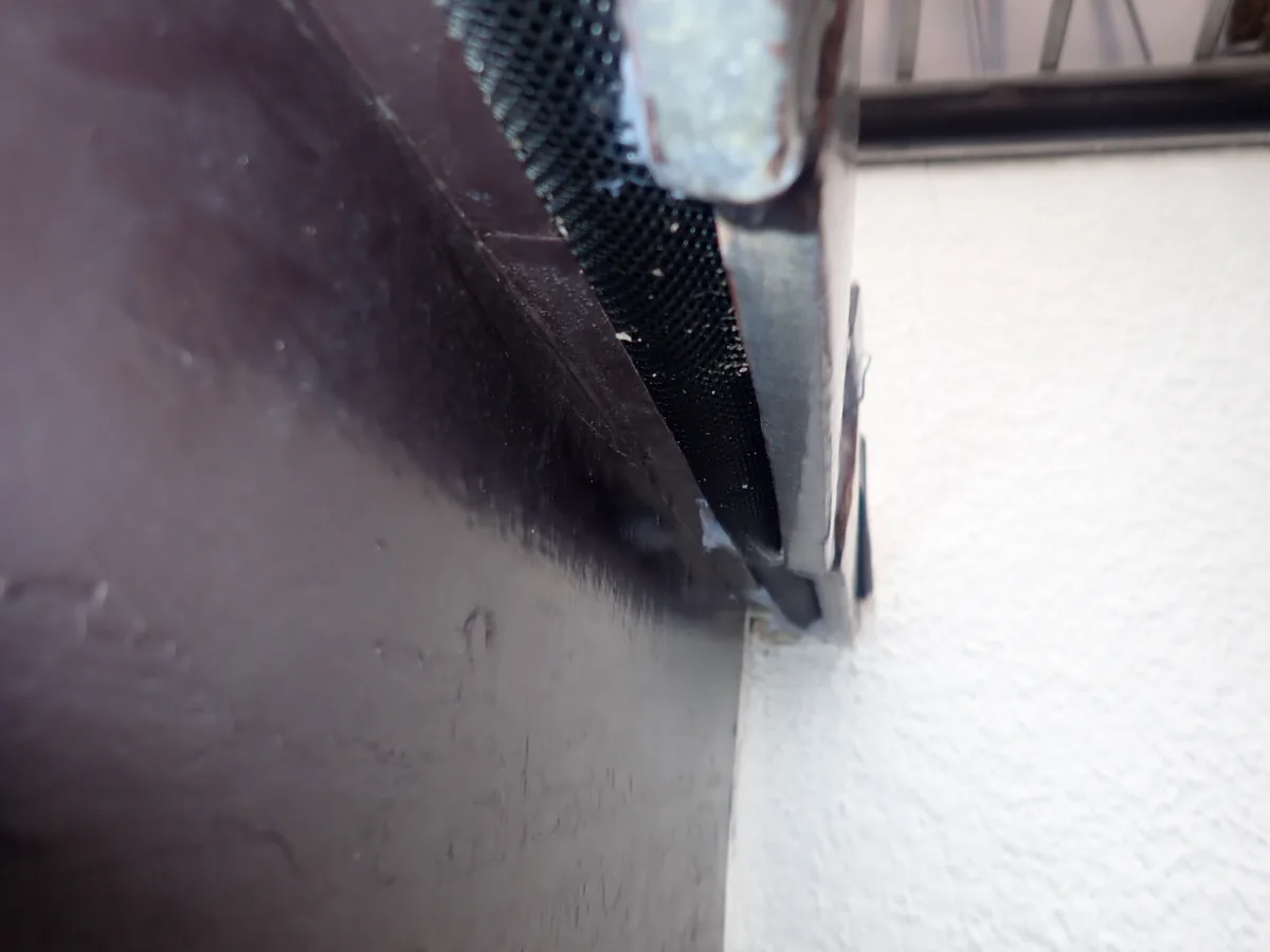 板金と白い外壁の間の細い隙間に、黒い穴あきの網を差し込んで塞いだ所