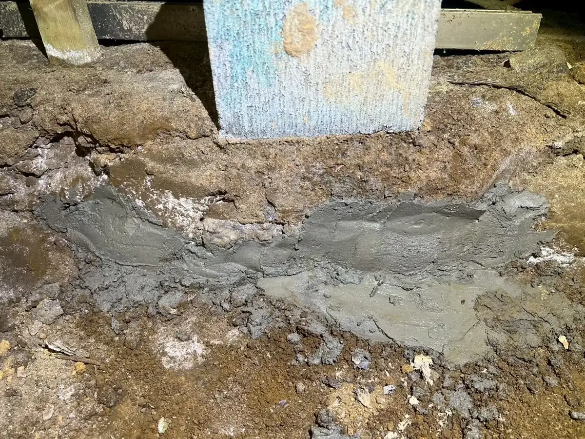 床下の束石まわりの地面を灰色の材料で固めた、足元の開口に対する施工跡